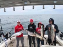 A group of people holding fish on top of a boat.
