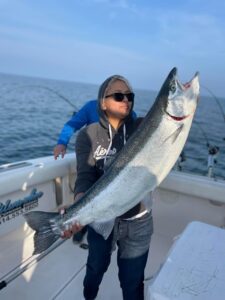 A woman holding a large fish on top of a boat.