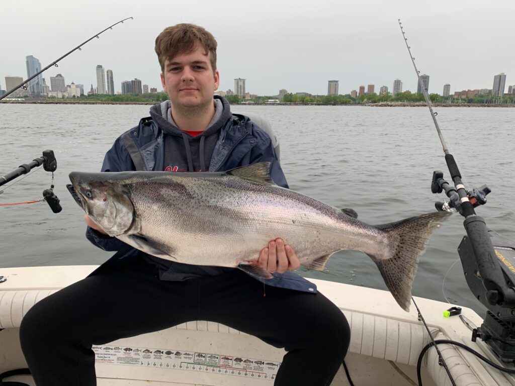 A man holding a large fish on top of a boat.